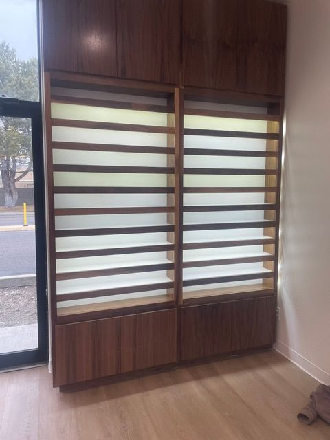 Wooden display cabinet with frosted glass panels in a bright room near a window and glass door