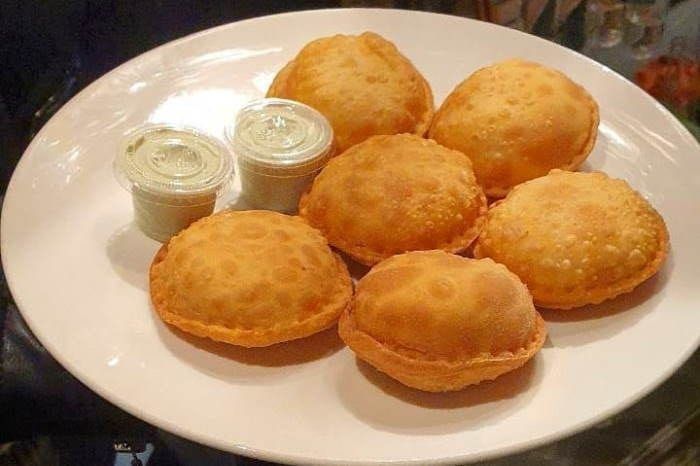 Plato de arepas fritas doradas con dos tazas pequeñas de salsa para mojar.