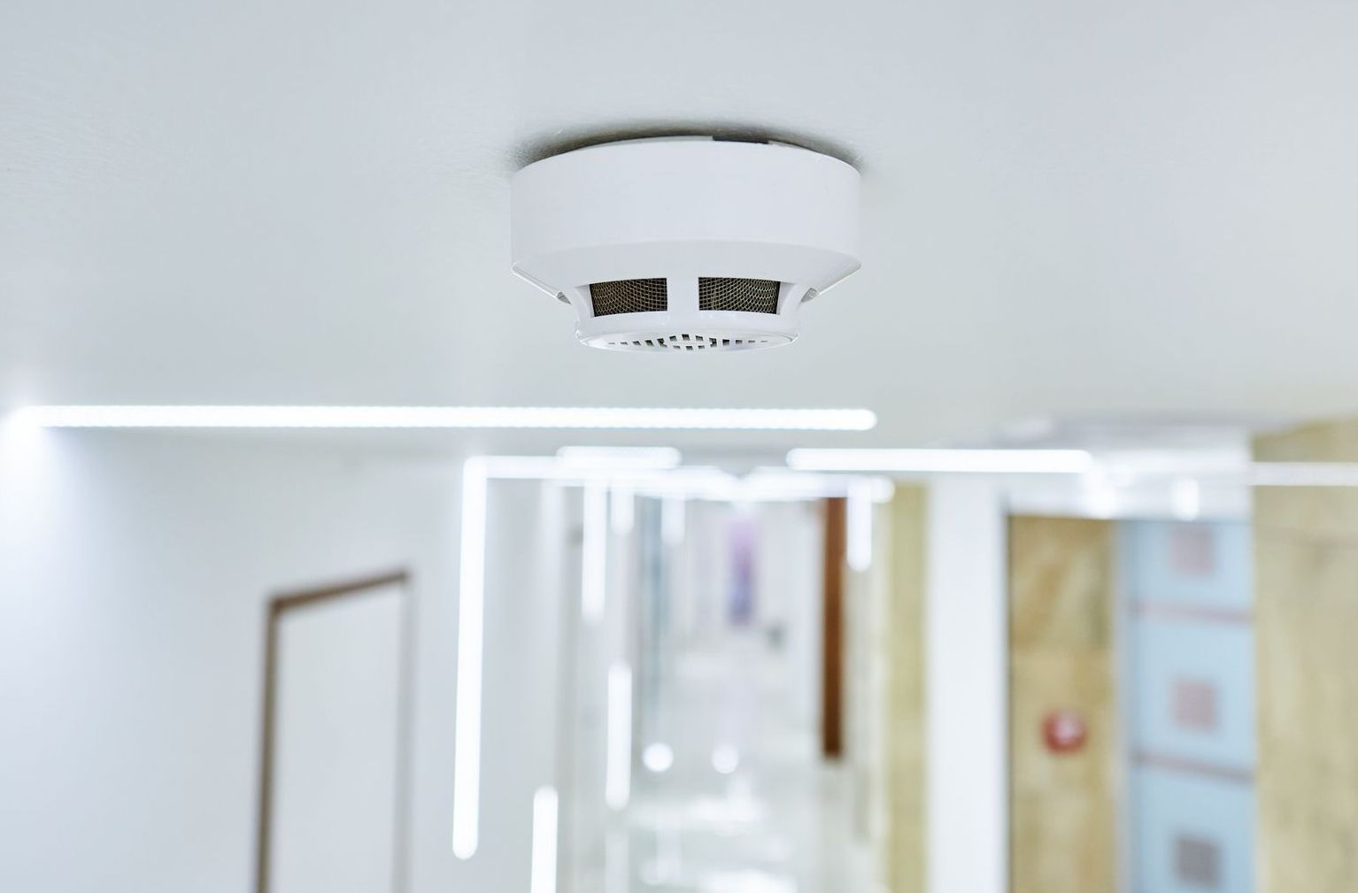 Property Maintenance The Curb Guy Mr Curber Arkansas A smoke detector is mounted on the ceiling of a hallway.