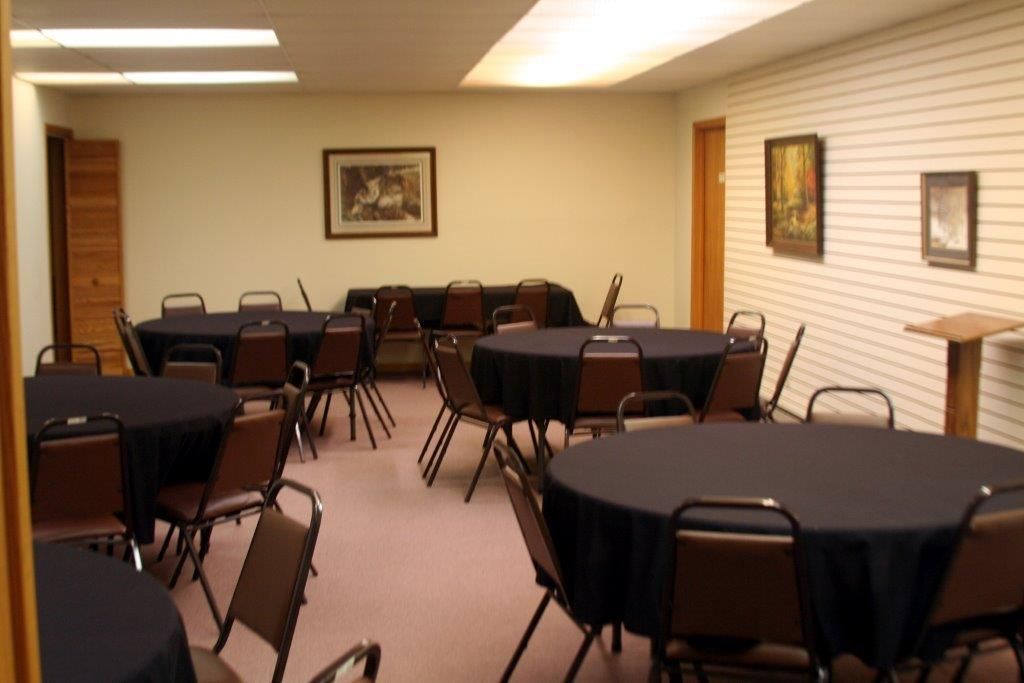Meeting room with round tables, black tablecloths, and chairs. Artwork hangs on the walls.