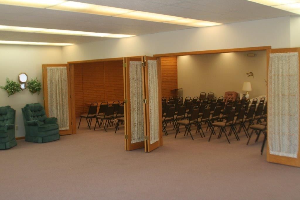 Interior of a funeral home chapel with rows of chairs and decorative wood paneling.