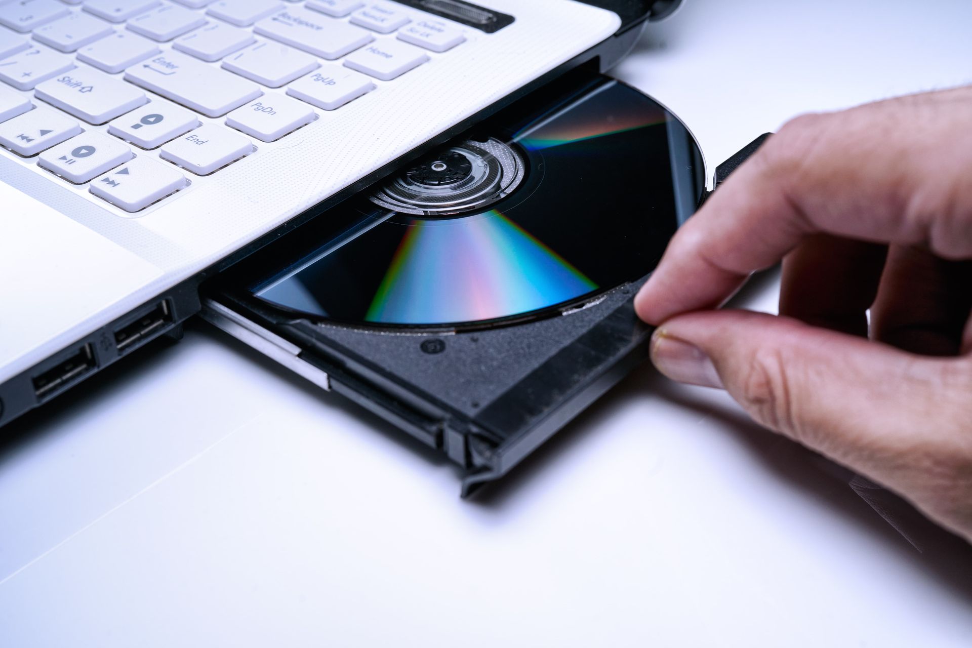 Hand inserting CD into laptop disc drive.