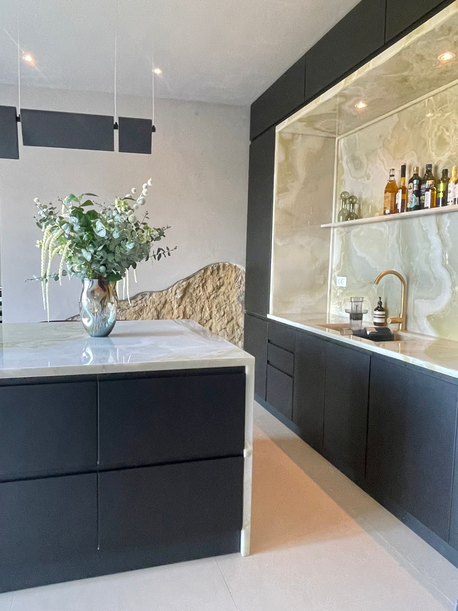 Modern kitchen with a dark gray island and cabinetry, featuring onyx