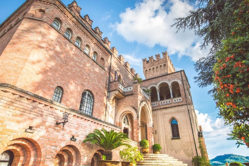 A brick castle with arched windows and a small tower on a sunny day.