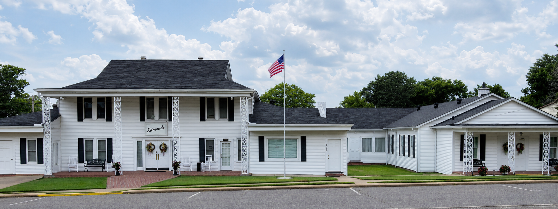 White church building with a steeple and American flag under a cloudy sky