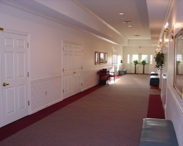 Hallway in a building with doors, beige walls, and a red carpet runner.