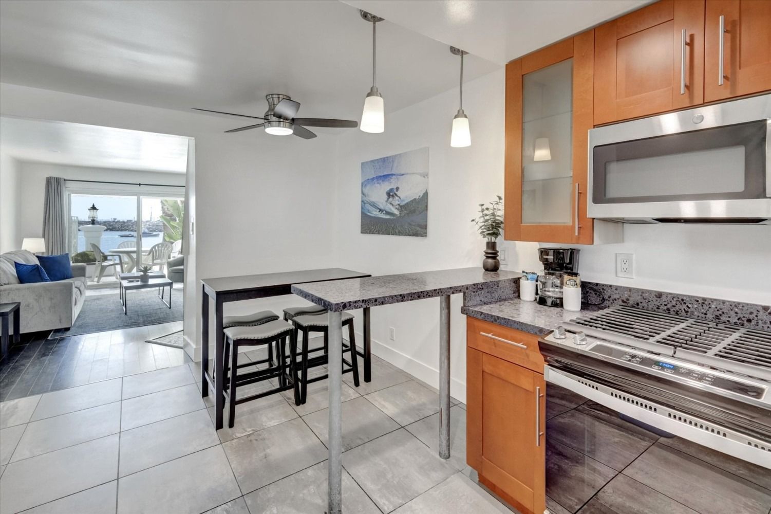 A kitchen with wood cabinets, stainless steel appliances, a stone breakfast bar, and a view into a living room.