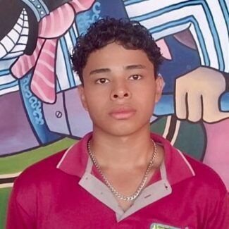 Young person in a red shirt standing before a colorful mural, looking at the camera.