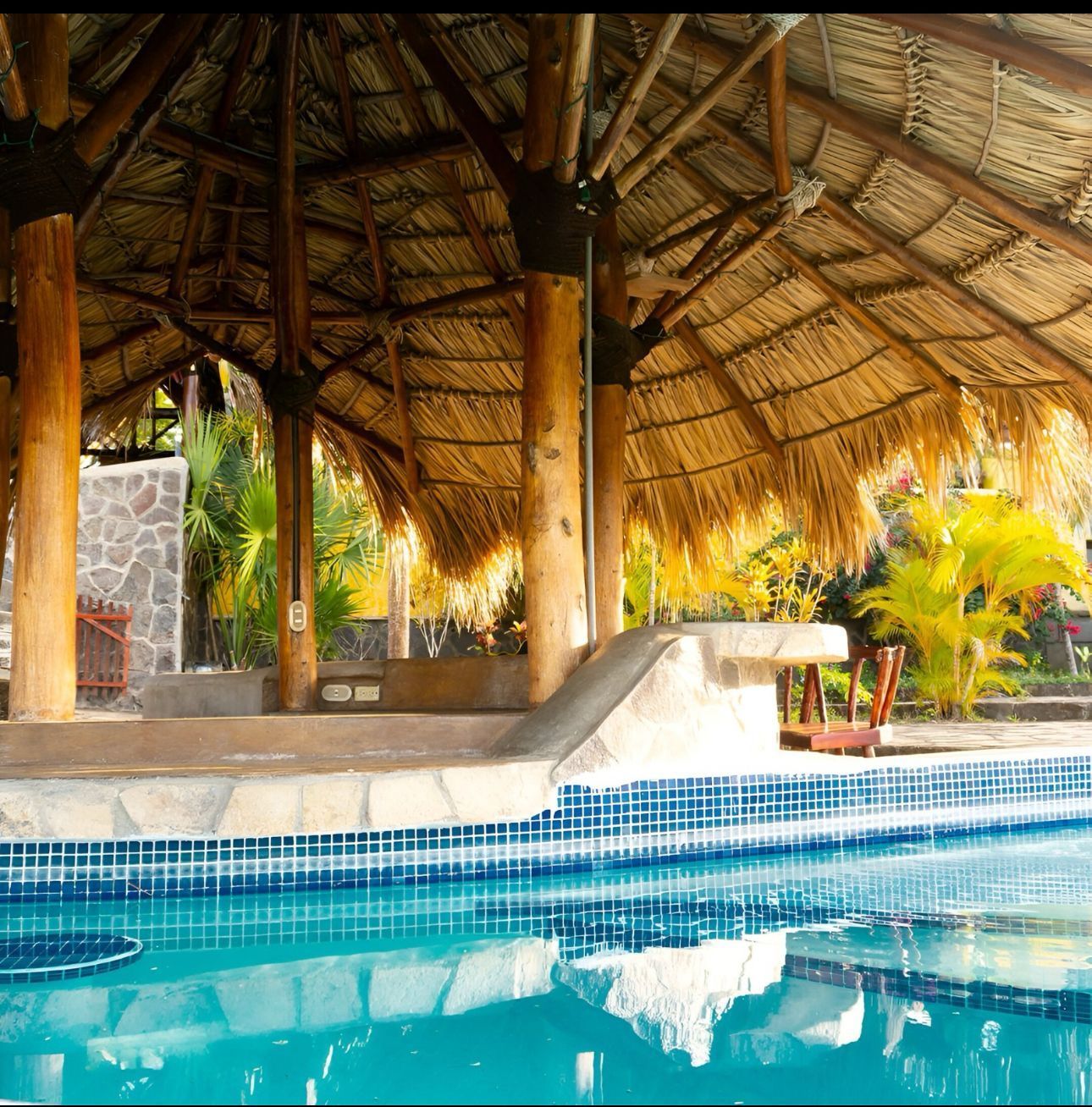 Thatched poolside cabana with turquoise water and tropical plants
