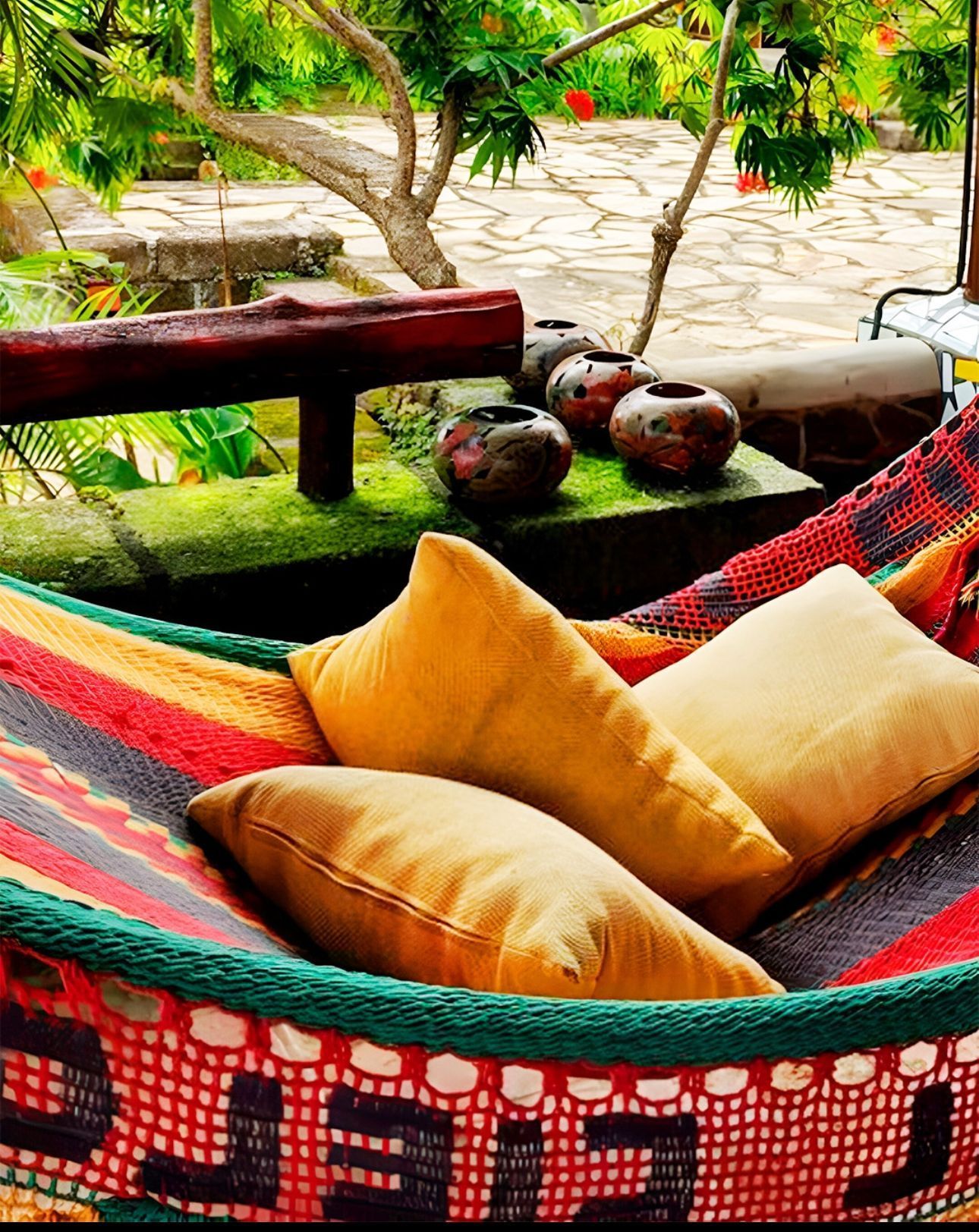 Colorful hammock with orange pillows in a leafy outdoor patio setting