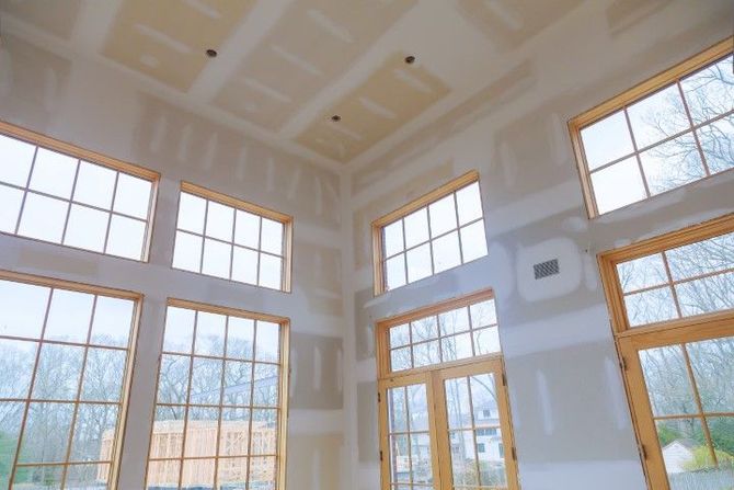 Bright, empty room with tall windows, white walls, and a high vaulted ceiling finished in light wood trim