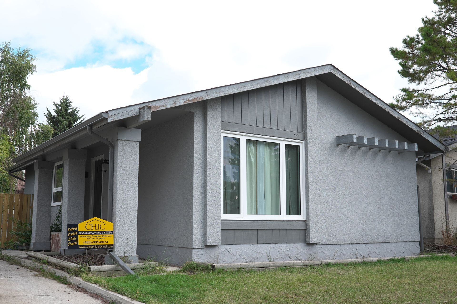 A gray house with a yellow sign in front of it that says