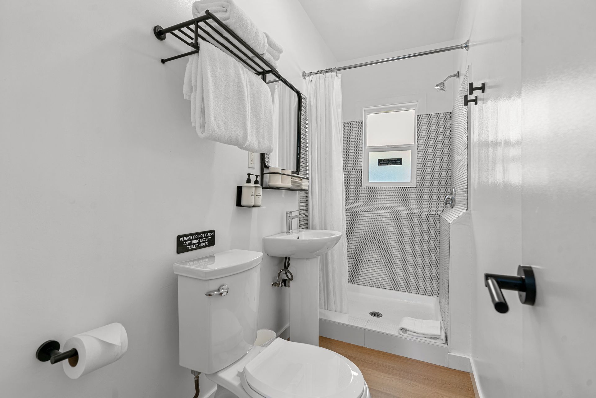 A bathroom with a toilet , sink and shower.