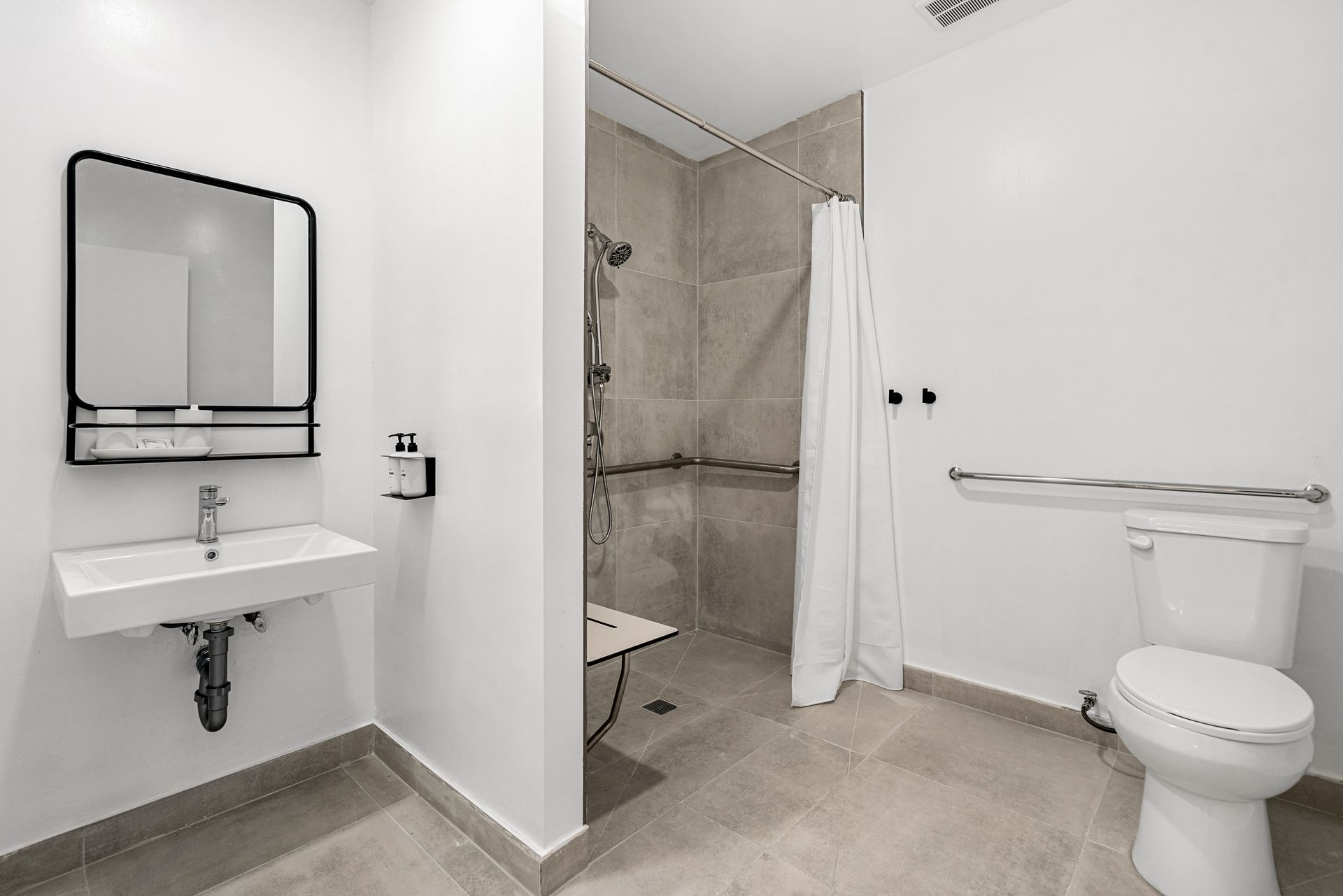 A bathroom with a toilet , sink , mirror and walk in shower.