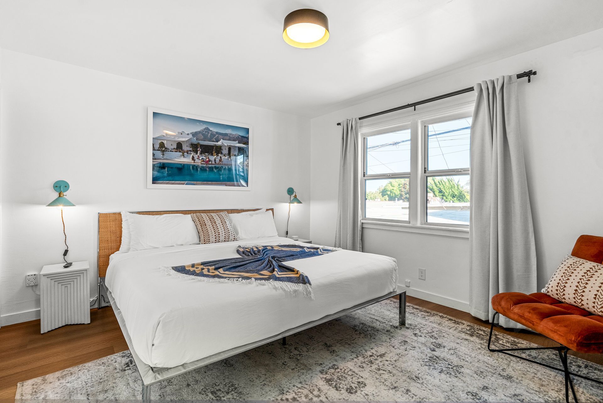 A bedroom with a bed , chair , nightstand , and window.