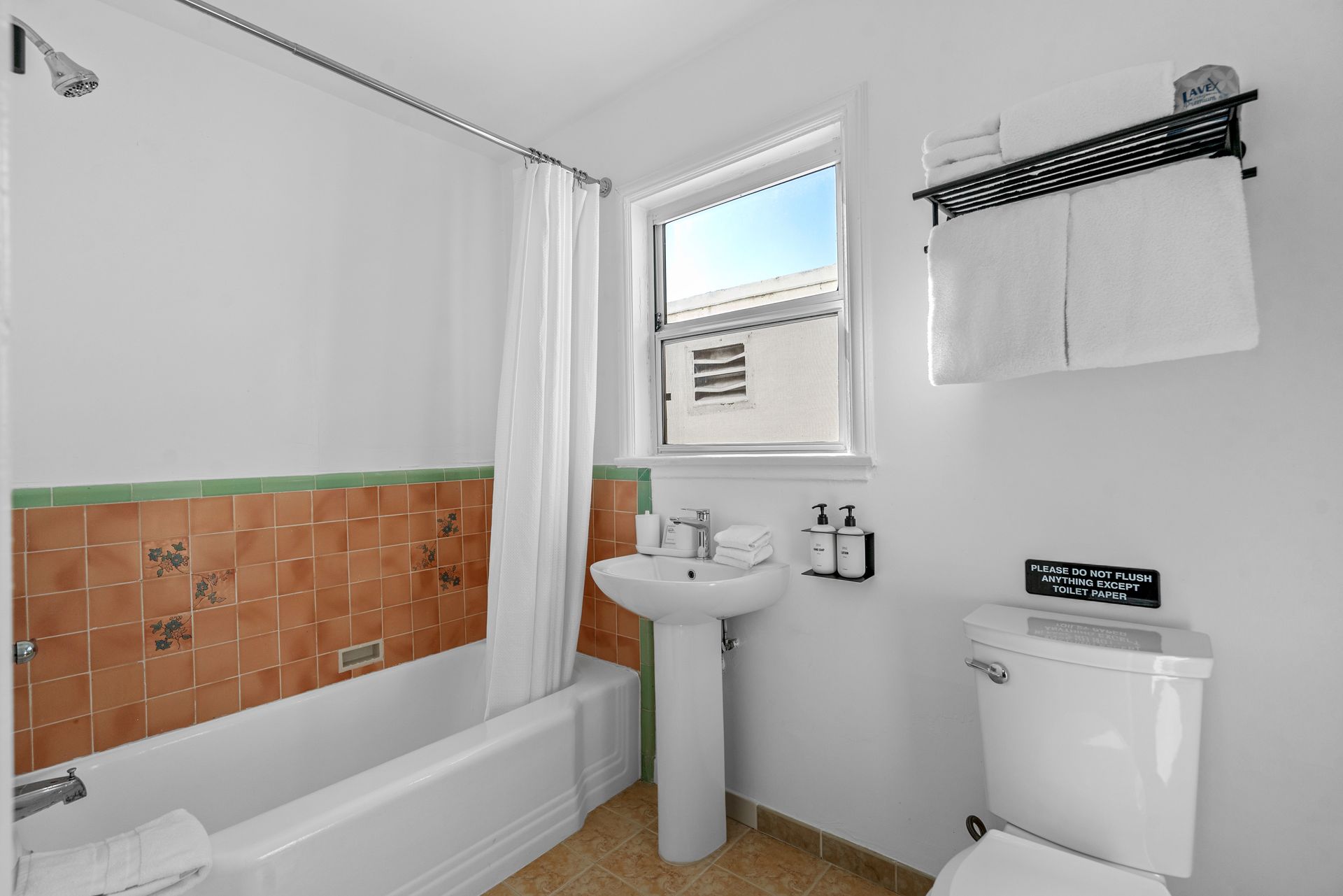 A bathroom with a sink , toilet , bathtub and window.