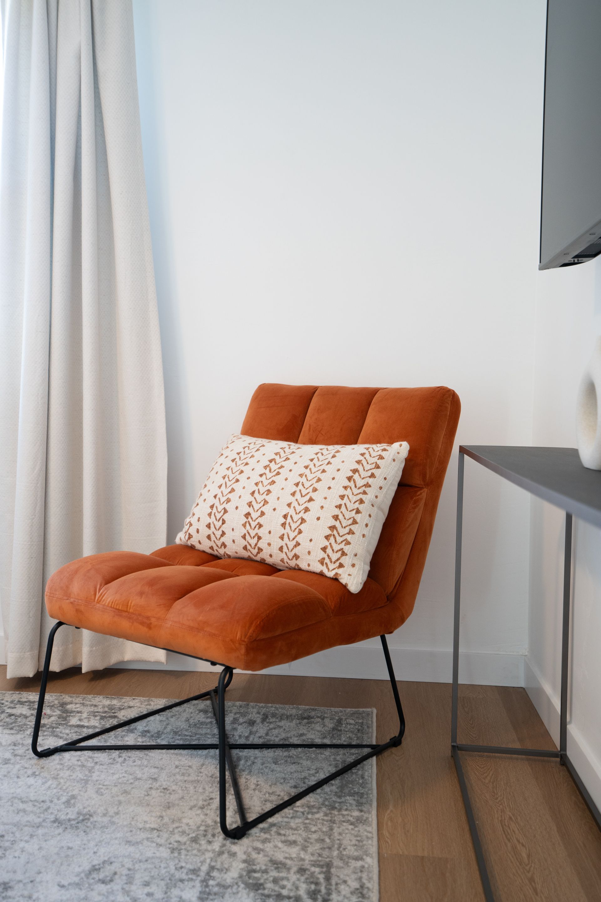 A chair with a pillow on it is sitting in a room next to a window.