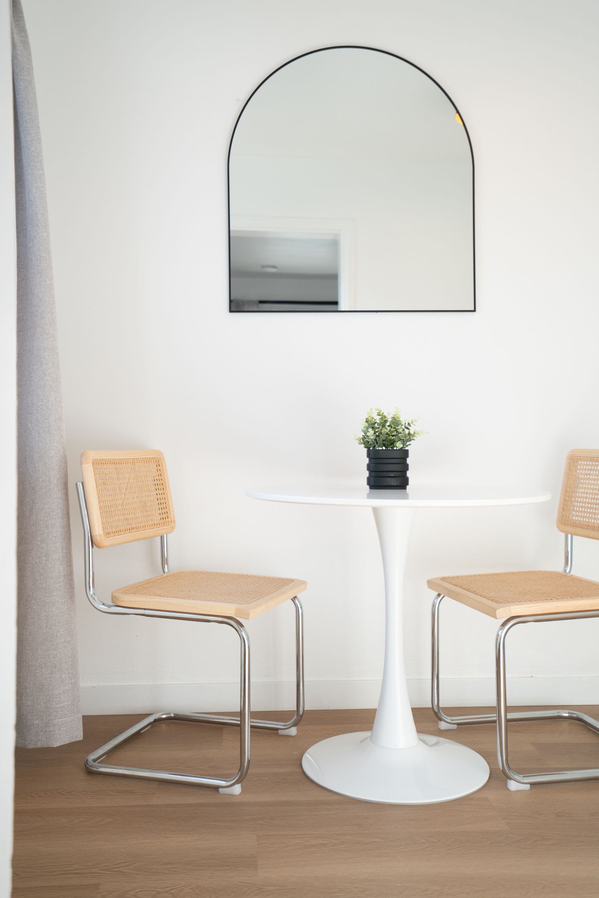 A white table with two chairs and a mirror on the wall.