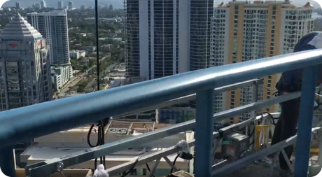 High-rise city view from a balcony with metal railing in the foreground