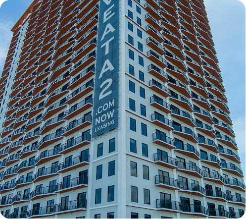 High-rise apartment building with curved balconies and a vertical blue “Avenida 2” sign