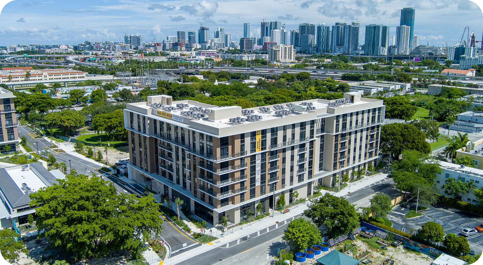Aerial view of a modern apartment building with a city skyline in the background.