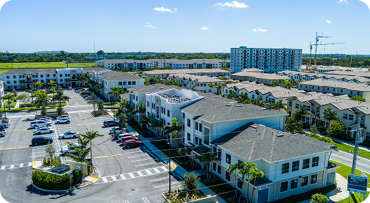 Aerial view of a suburban office park with parking lots, low-rise buildings, and a construction site in the distance