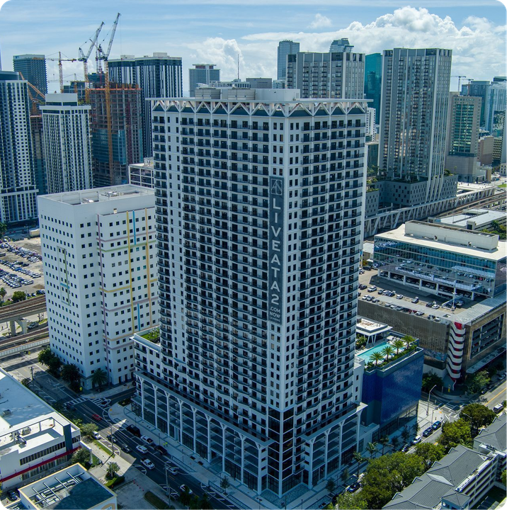 Aerial view of a high-rise city block with a tall black-and-white apartment tower under construction.