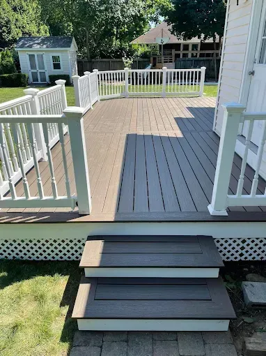 Back deck with gray steps, white railings, and a fenced yard in the background