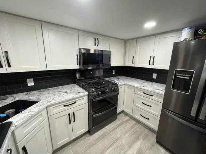 Modern white-and-black kitchen with stainless steel appliances and gray wood-look floor