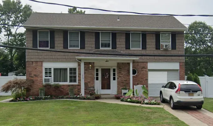 Two-story brick house with a white garage and a car parked in the driveway