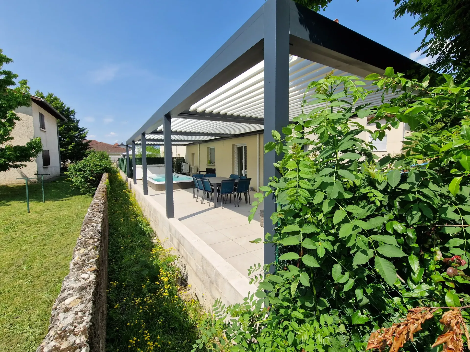 une maison avec une terrasse couverte avec une table et des chaises .