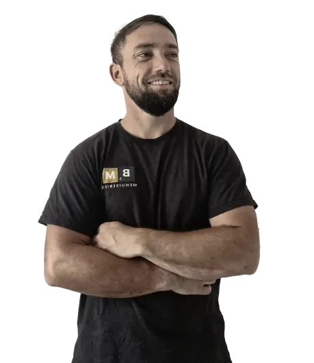 Un homme, les bras croisés, vêtu d'un t-shirt noir, sourit et regarde vers le ciel.