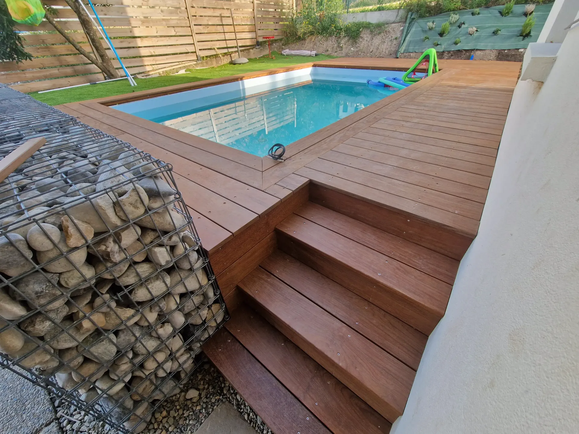 une terrasse en bois avec des escaliers menant à une piscine .