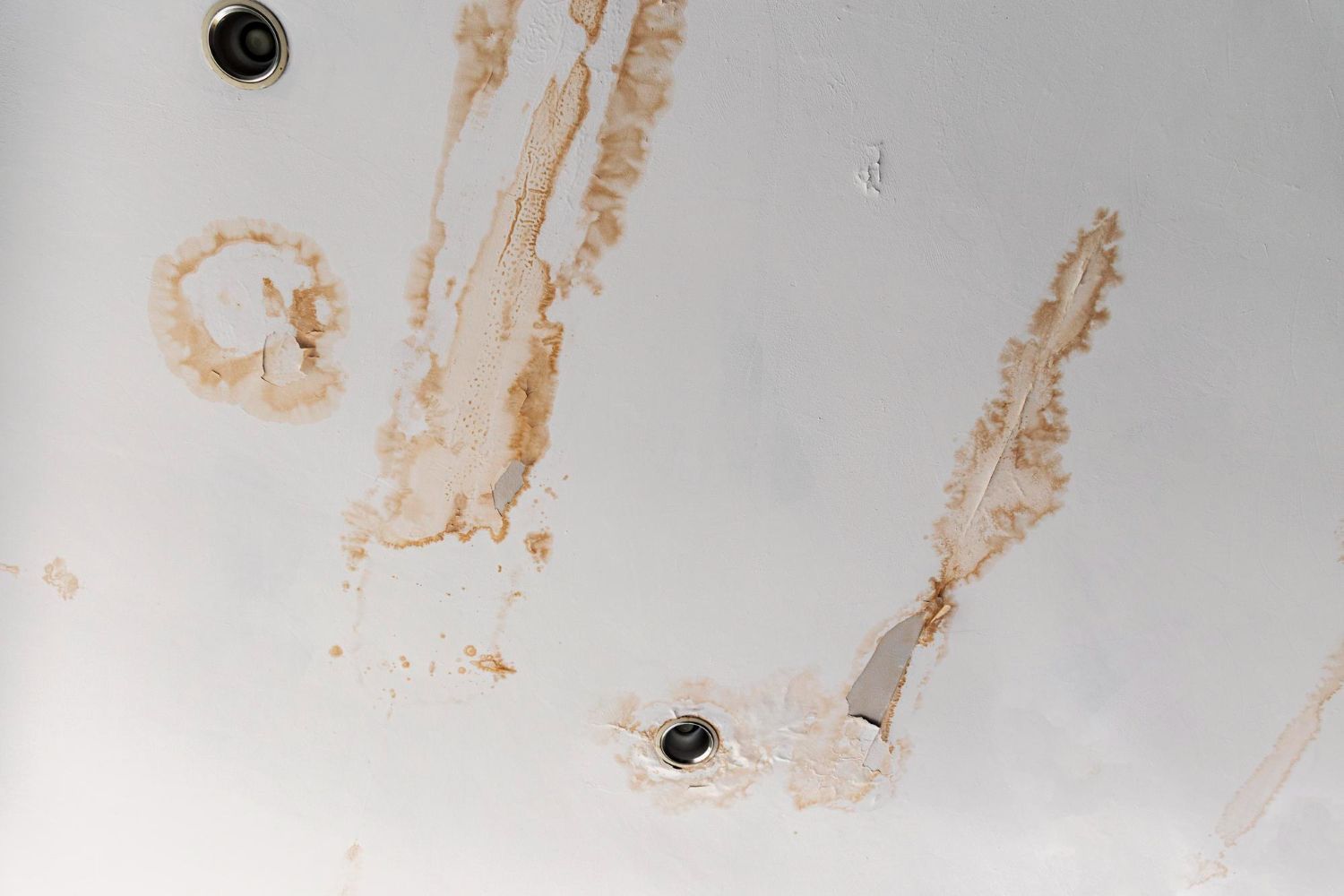White surface with several tan stains and a small black screw hole near the bottom center