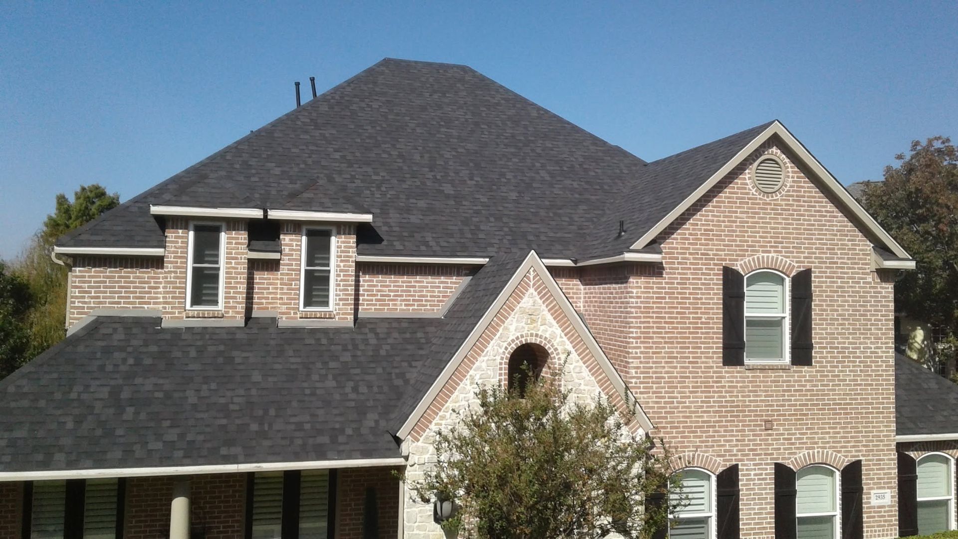 Suburban brick house with dark gray roof and white trim, front-facing view