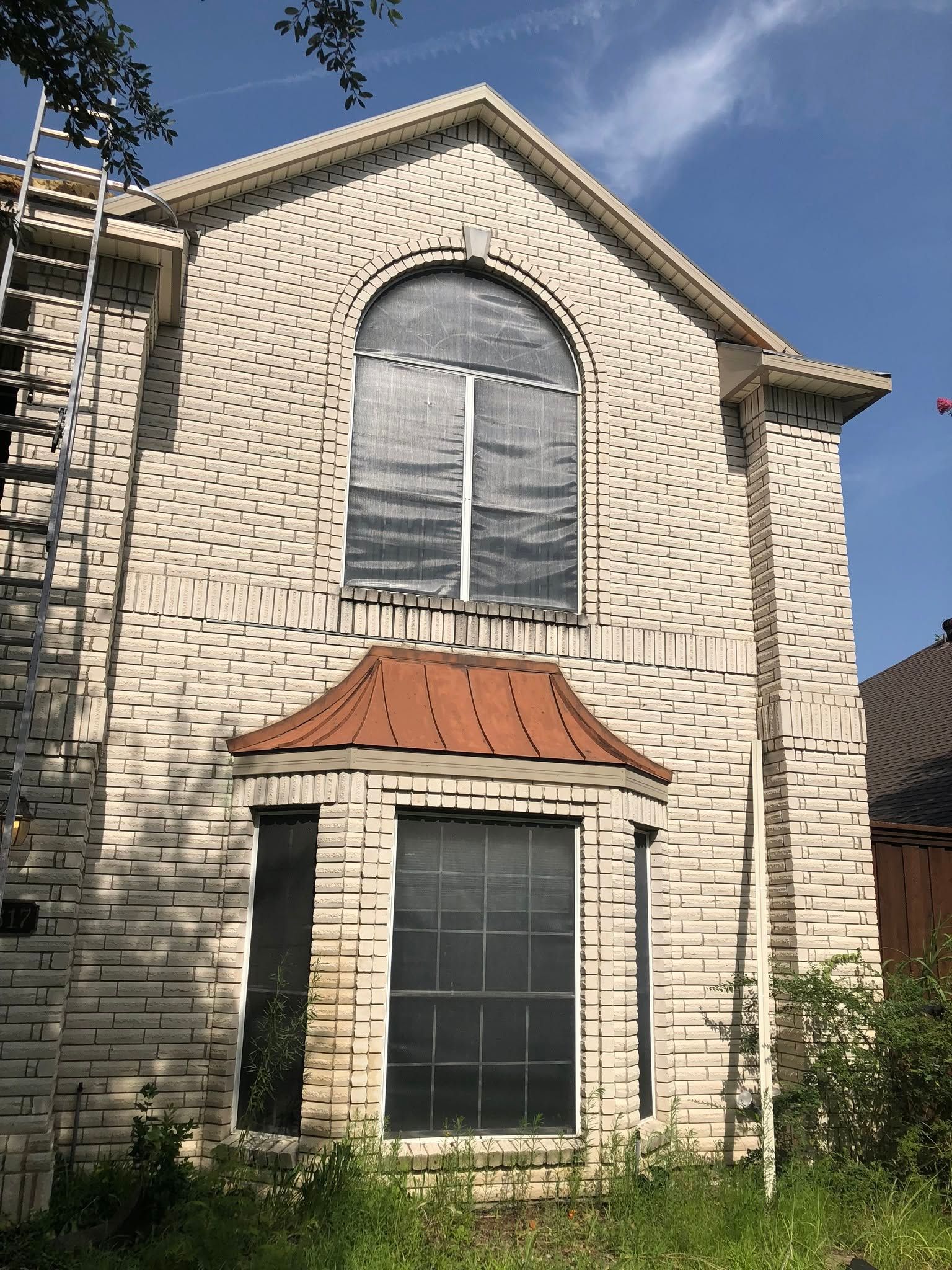 Two-story stone house with arched upper window and small red awning over the lower window