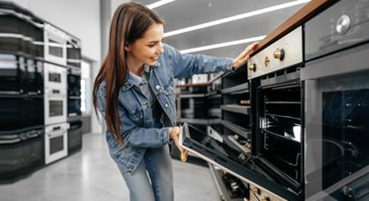 Woman loading a built-in oven in a showroom kitchen display