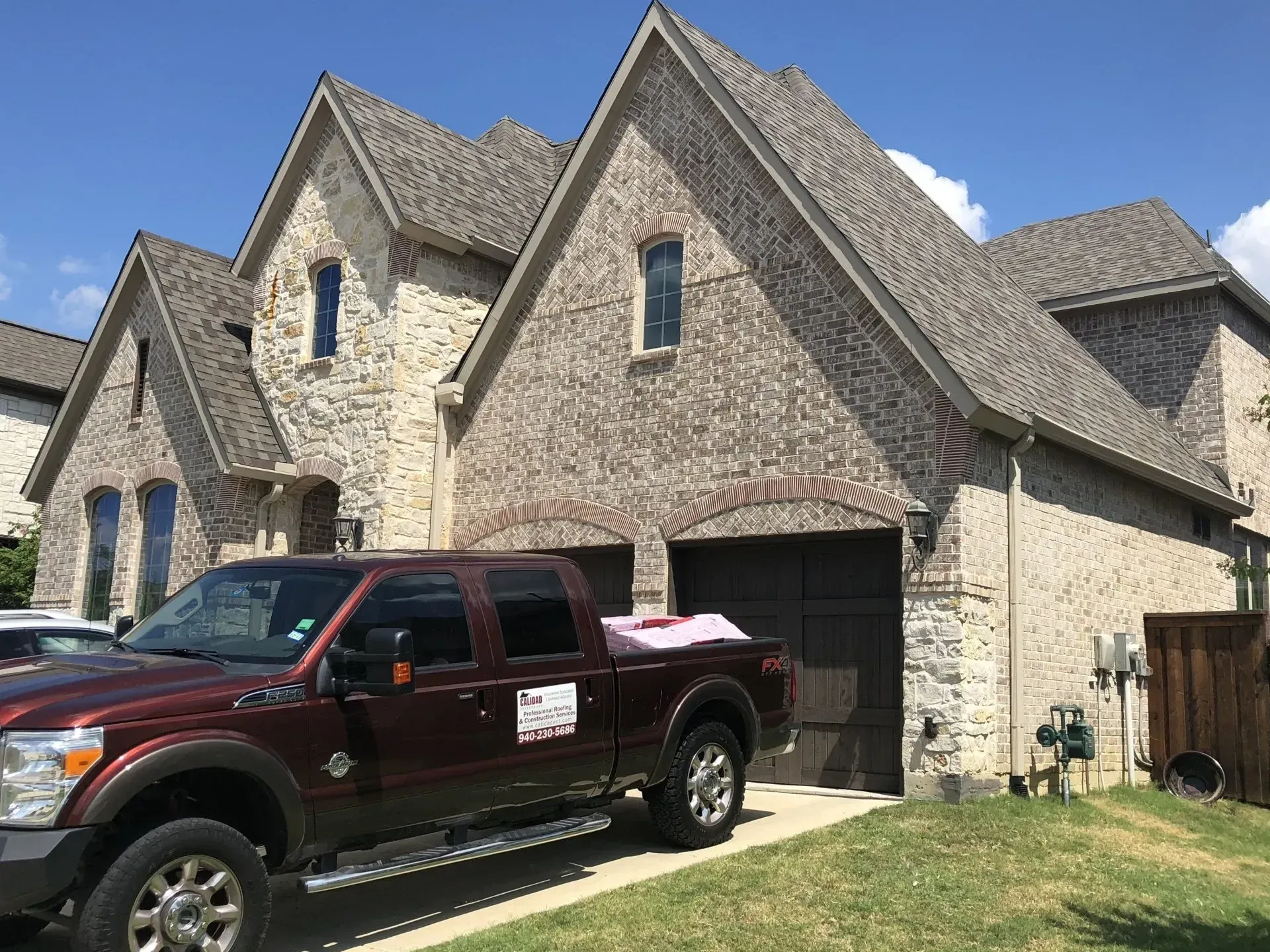 Stone suburban house with steep gables and a maroon pickup parked in the driveway