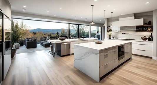 Modern open-plan kitchen with white island, wood floors, and mountain-view windows