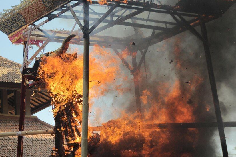 Large fire raging in a wooden structure, with flames and thick smoke under a metal canopy
