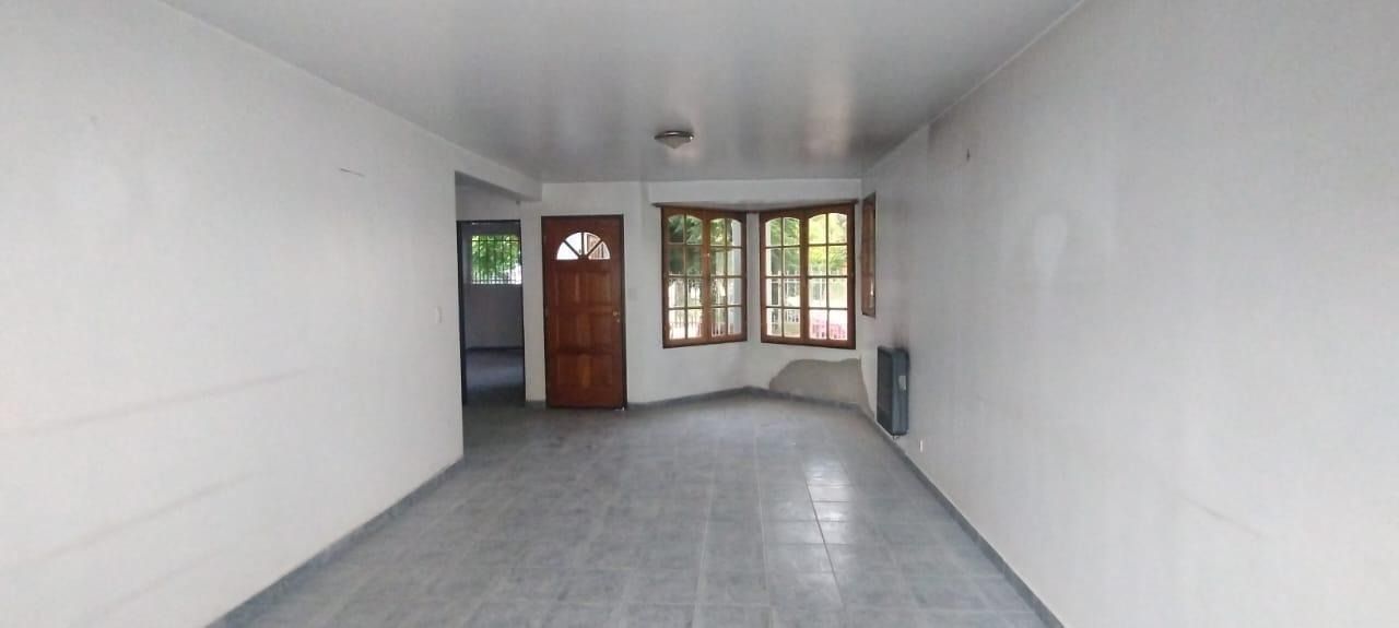 Casa blanca de dos pisos con un patio delantero cercado y árboles a ambos lados al atardecer.