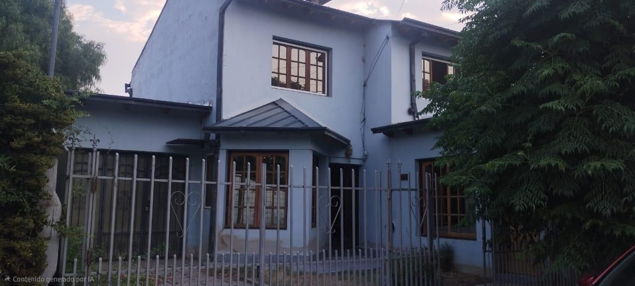Casa blanca de dos pisos con un patio delantero cercado y árboles a ambos lados al atardecer.