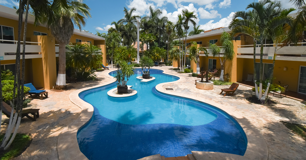 Una gran piscina rodeada de habitaciones y palmeras.