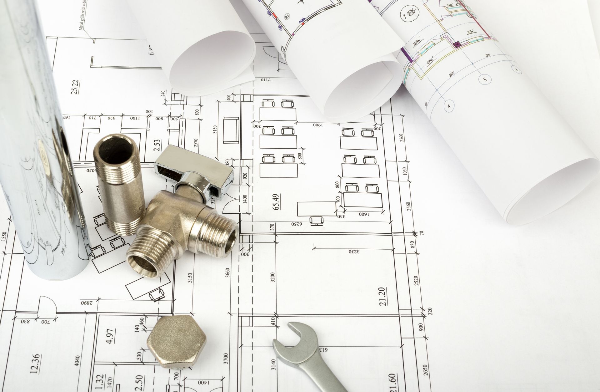 Blueprints with plumbing hardware and a wrench.