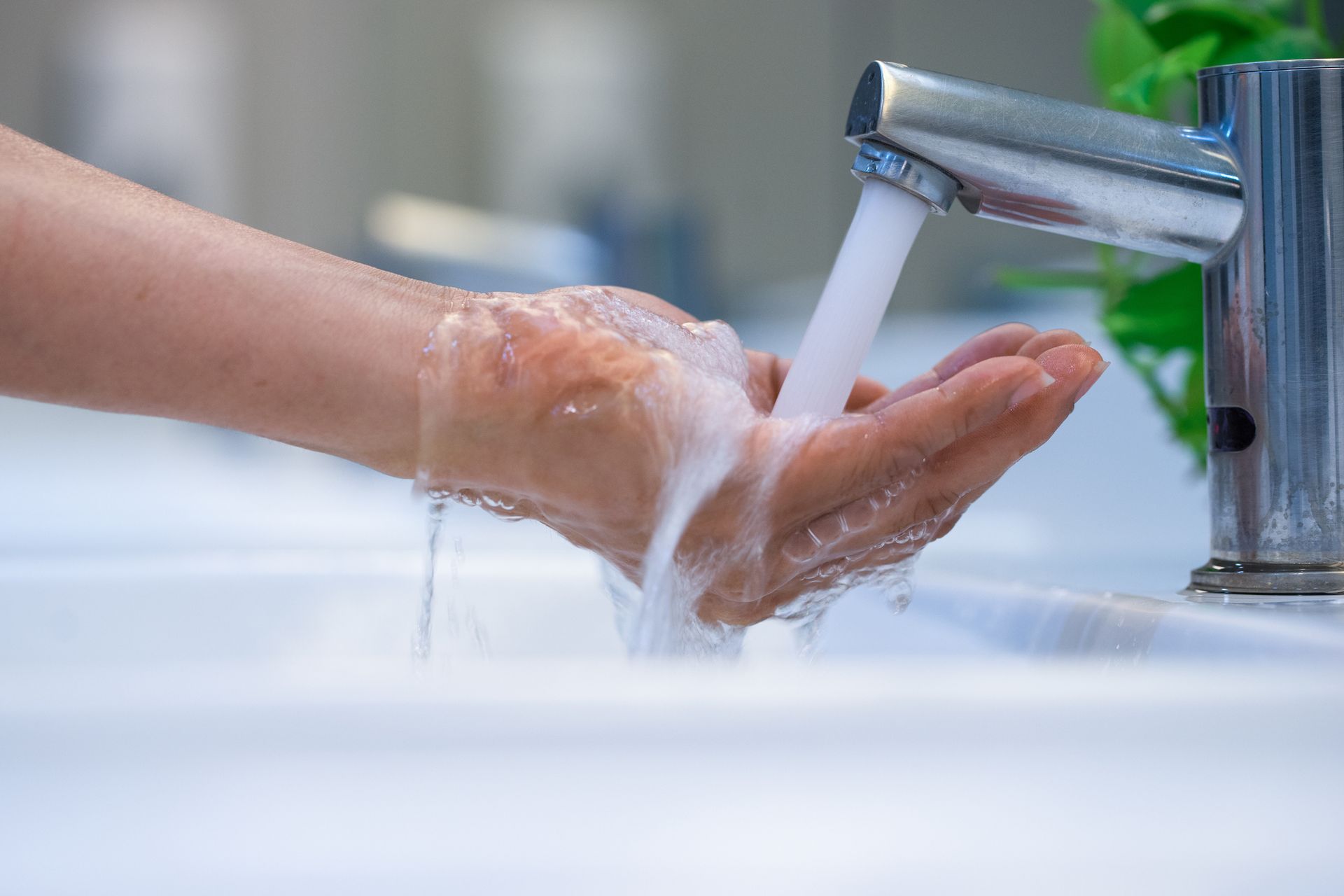 Person washing hands with soap and water at a sink.