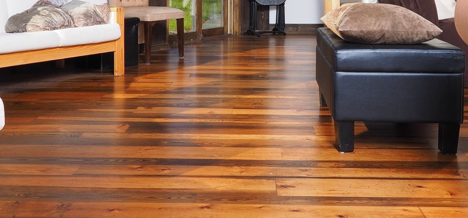 A Living Room With a Wooden Floor and a Black Ottoman — Totally Flooring Gold Coast In Bundall, QLD