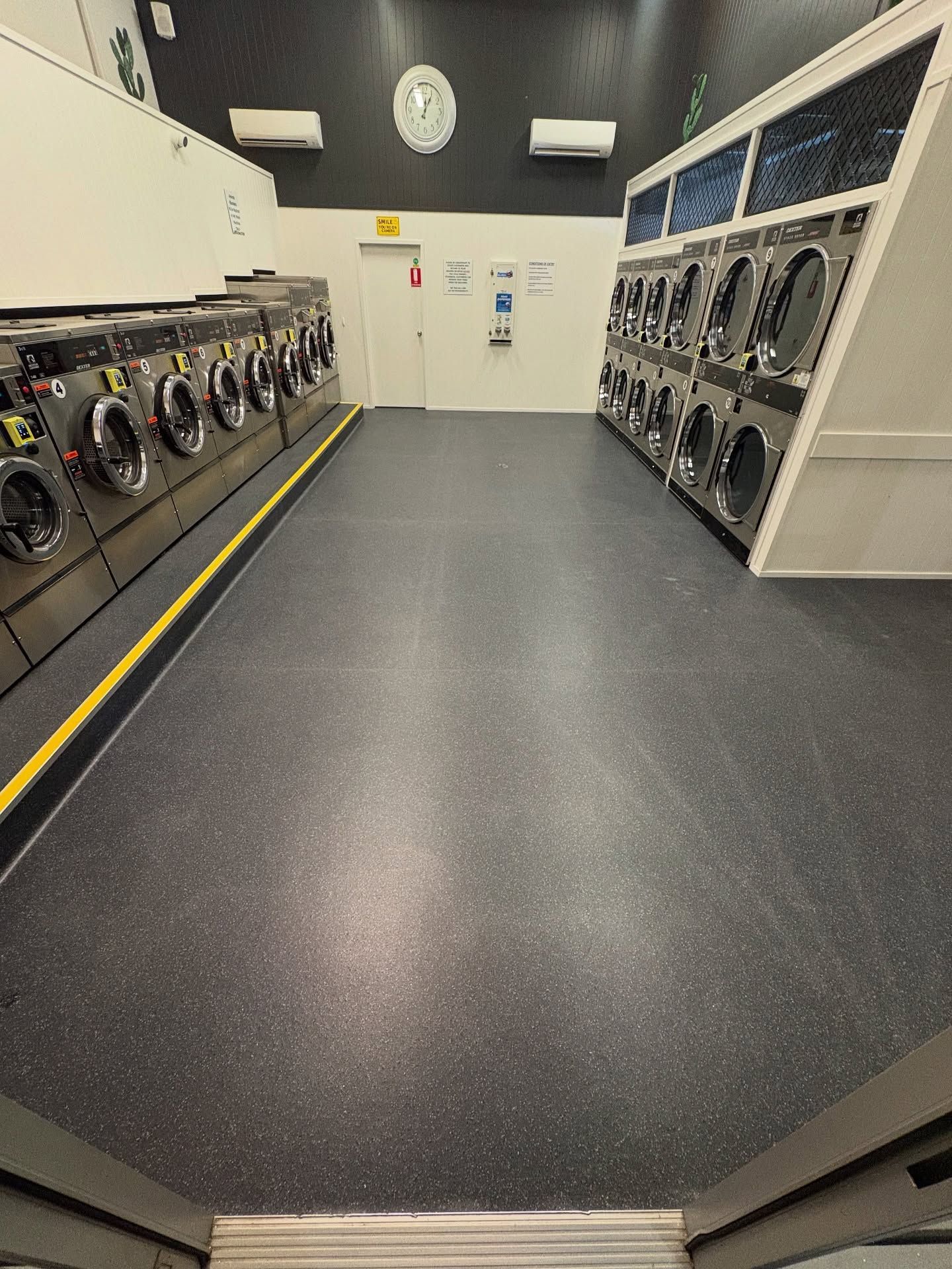 A laundromat interior with rows of washing machines — Totally Flooring Gold Coast In Bundall, QLD