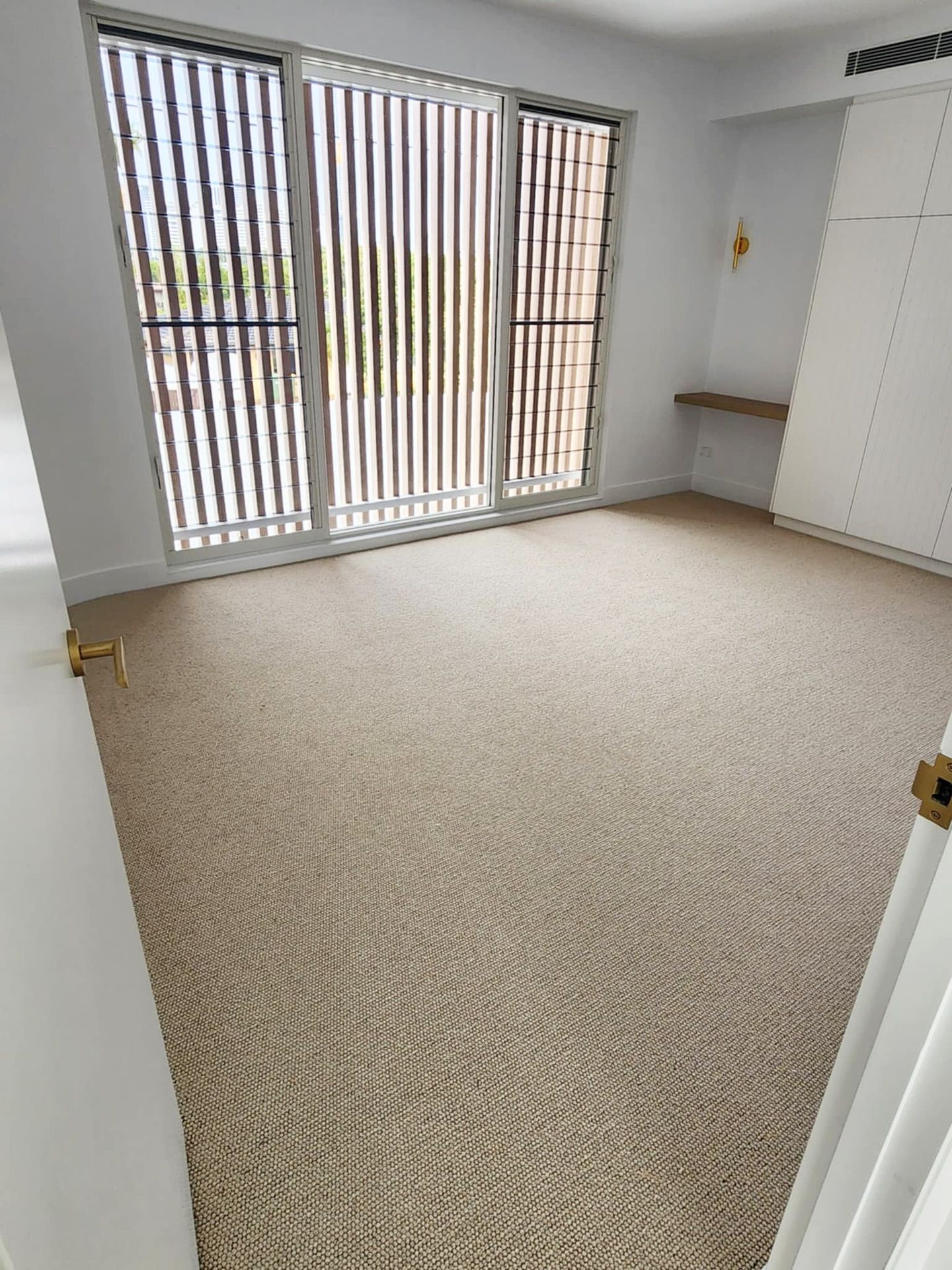 Empty room with beige carpet, large windows with vertical blinds — Totally Flooring Gold Coast In Bundall, QLD