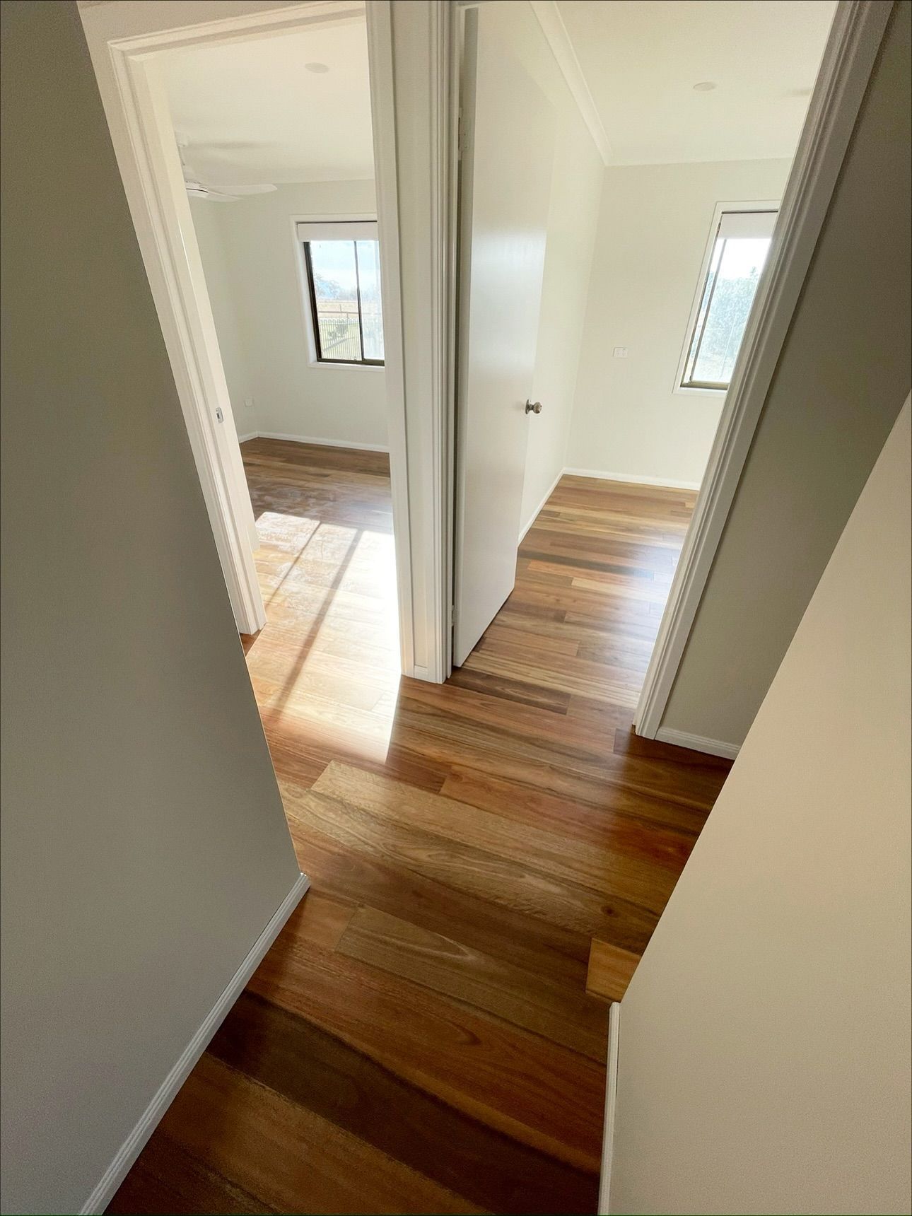 Hallway with wood floors, two doorways leading to rooms with windows — Totally Flooring Gold Coast In Bundall, QLD