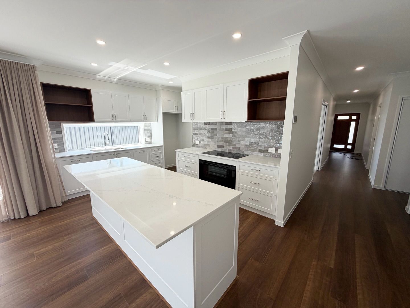 Modern kitchen with white cabinets, island, and dark wood floors — Totally Flooring Gold Coast In Bundall, QLD